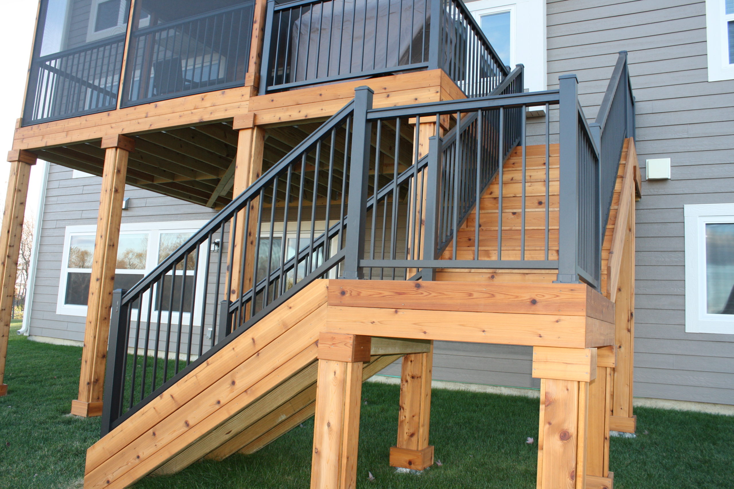 Black Aluminum Railing on Deck Staircase Black aluminum railing with vertical balusters on wooden deck stairs