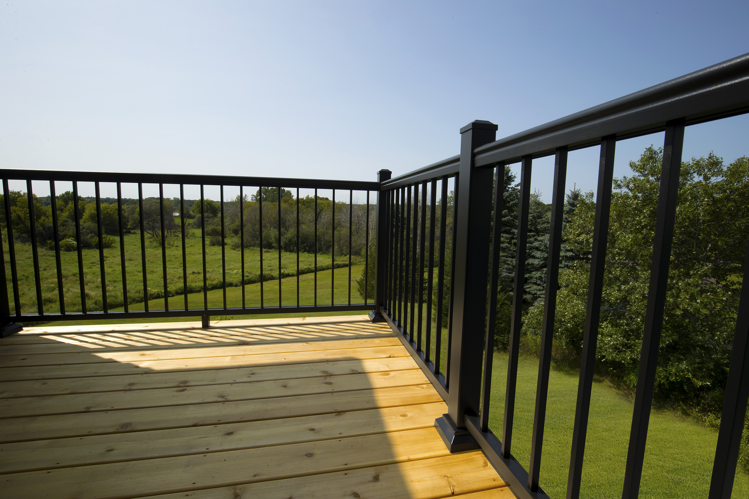 Black Aluminum Railing on Residential Wooden Deck Black aluminum railing on wooden deck with green landscape view