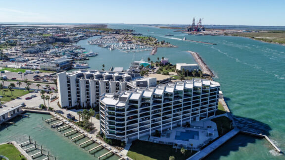 Waterfront condominium complex with white aluminum balcony railings and pool