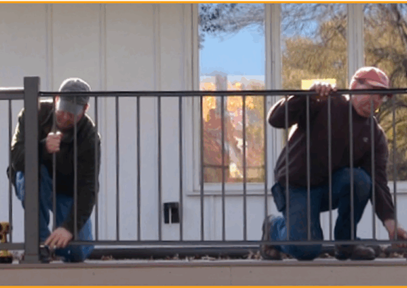 Workers installing black aluminum railing on residential deck